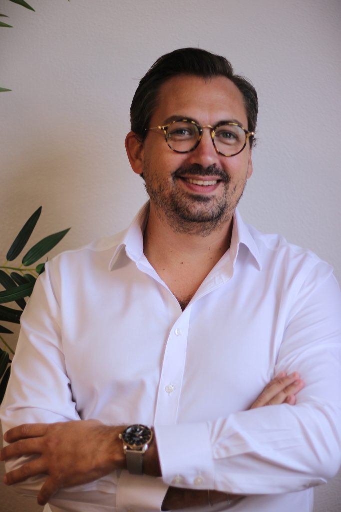 Photo professionnelle de Maxime Lemallier, directeur Général de Interlac France qui souri à la caméra avec les bras croisés.